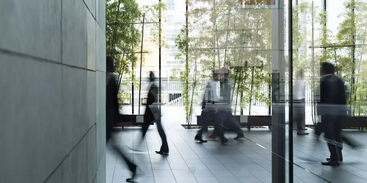 Detail eines Büro Gebäudes mit Pflanzen und Menschen in Bewegung