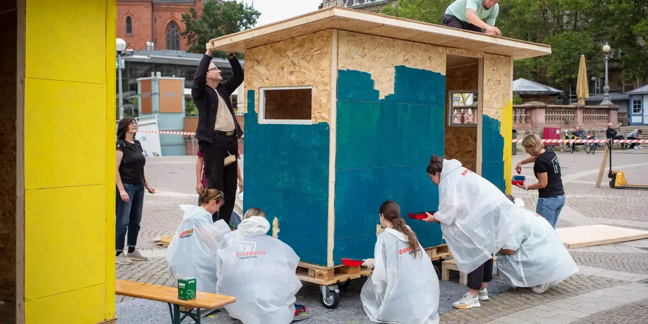 Commerz Real Mitarbeiter bauen in Teamarbeit Little Home Obdachlosen-Unterkünfte