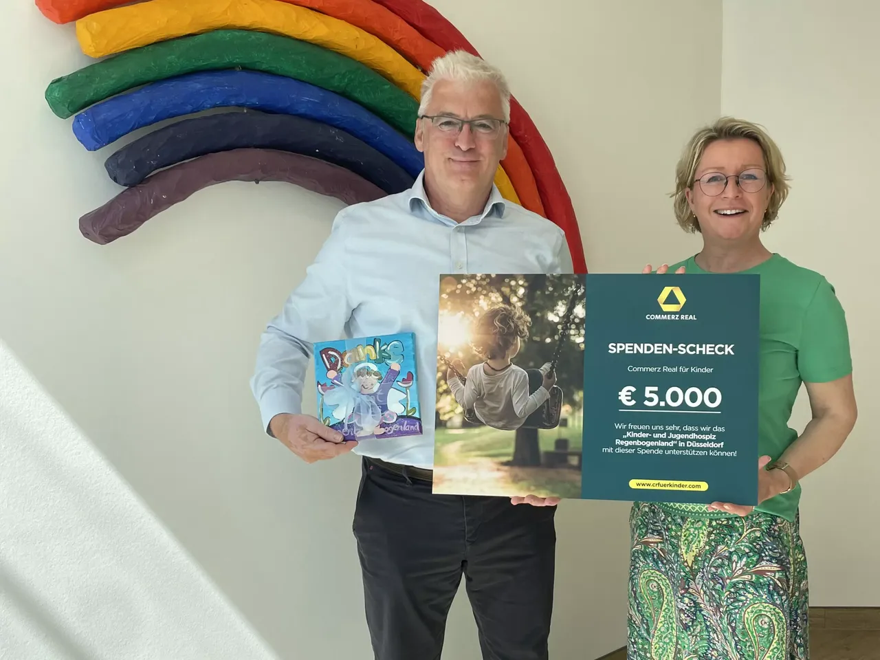 Es wird die Spendenübergabe im Rahmen der Aktion CR für Kinder für die Organisation Regenbogenland dargestellt.