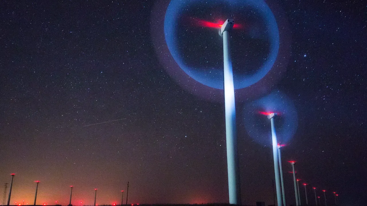 Es wird das nächtliche Blinken von Windkrafträdern in einem Windpark dargestellt.