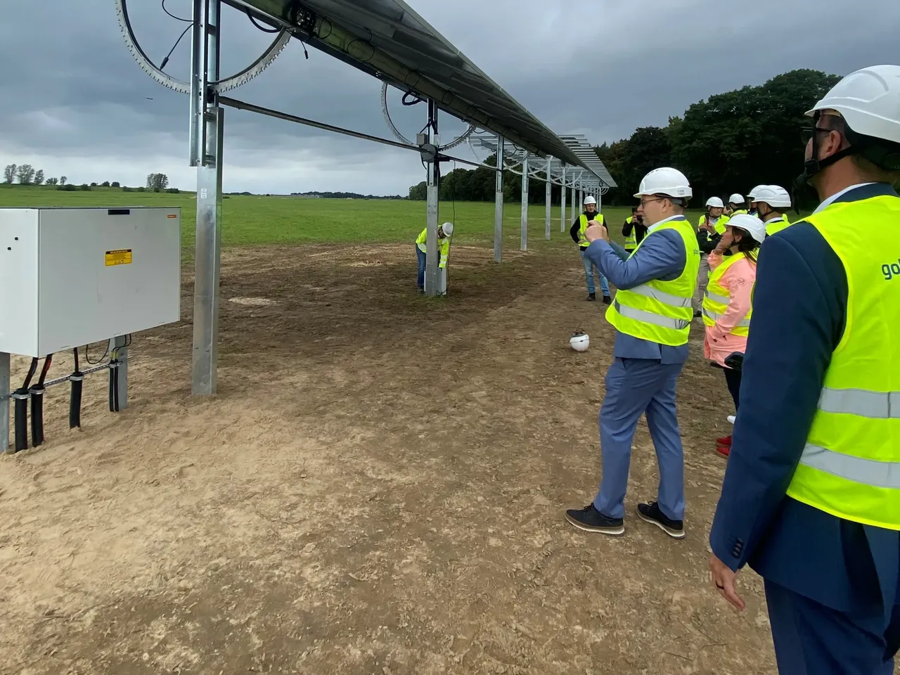 Es werden mehrere Projektbeteiligte im Gespräch vor den Solarmodulen des Agri-PV-Projekts in Berlin-Schönefeld dargestellt.