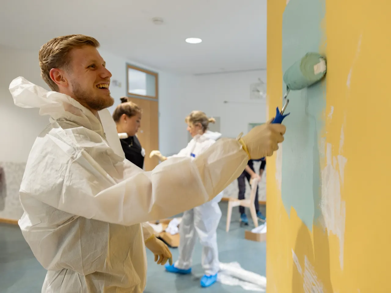 Es werden Mitarbeiterinnen und Mitarbeiter bei Malerarbeiten im Rahmen des Commerz Real Social Days 2024 in Wiesbaden dargestellt.