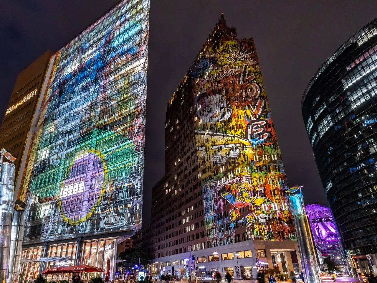 Es wird der Potsdamer Platz in Berlin dargestellt, der neben vielen anderen Gebäuden und Wahrzeichen während des sogenannten Festival of Lights spektakulär illuminiert wird.