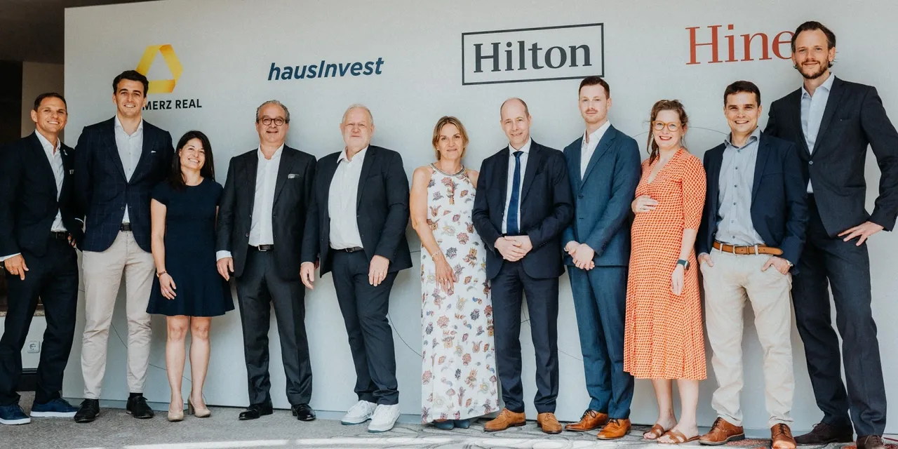 Es wird eine Gruppenbild im Rahmen der Vertragsunterzeichnung des Mietvertrages mit Hilton und der Commerz Real dargestellt.