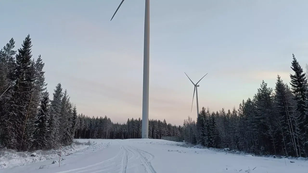In einer Schneelandschaft wird die Außenansicht von zwei Windrädern des klimaVest Windparks Fennica in Finnland abgebildet.