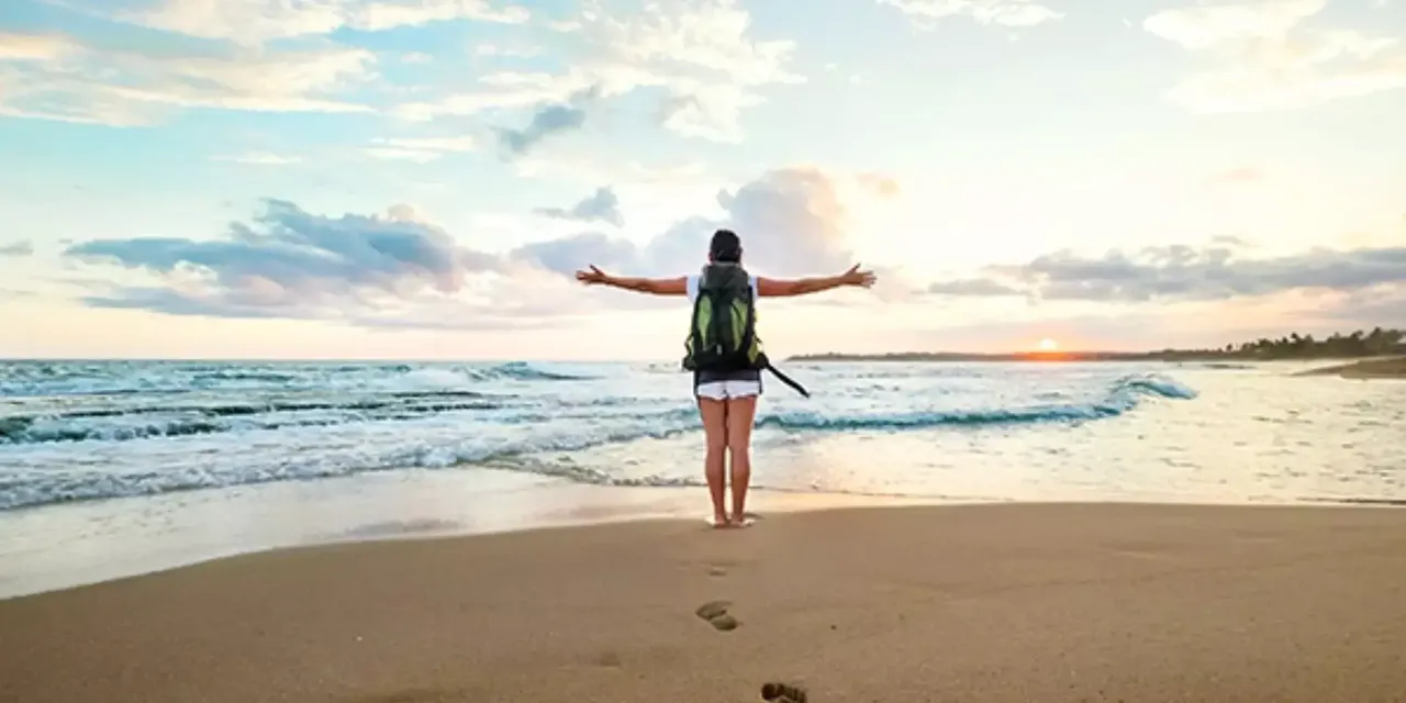 Frau mit ausgebreiteten Armen am Meer