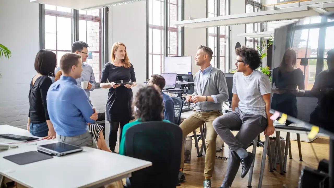 Es werden Menschen im Büroalltag in Gesprächen abgebildet