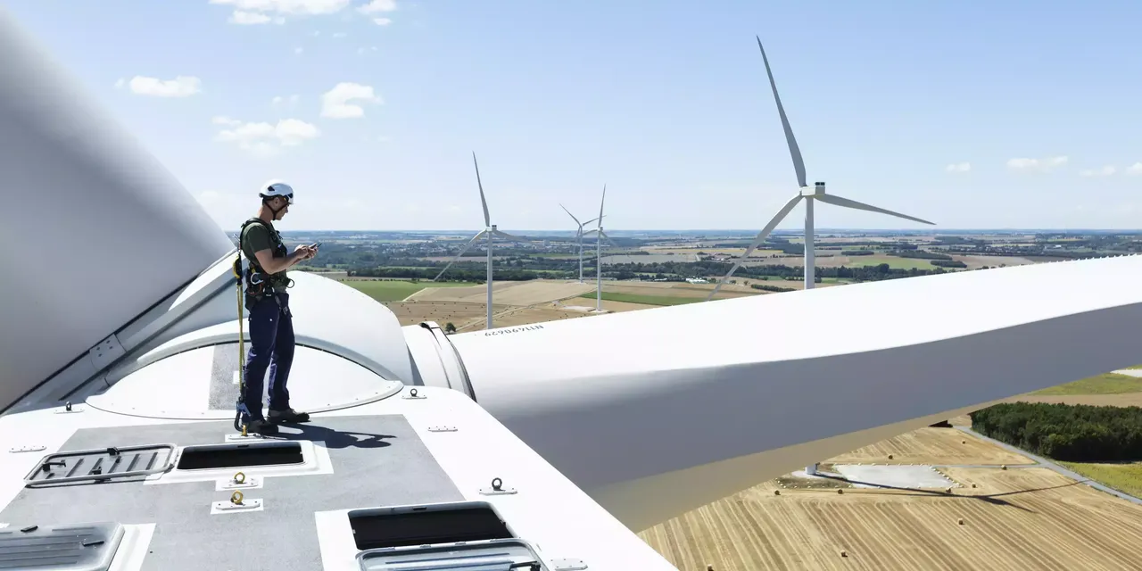 klimaVest: Windrad mit Mann mit Helm im Windpark ToutVent