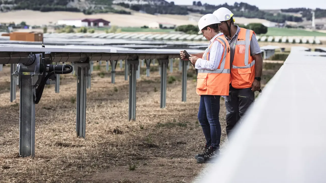 Nahaufnahme von zwei Arbeitern im klimaVest-Asset Solarpark Tordesillas mit orangenen Westen und weißen Helmen.