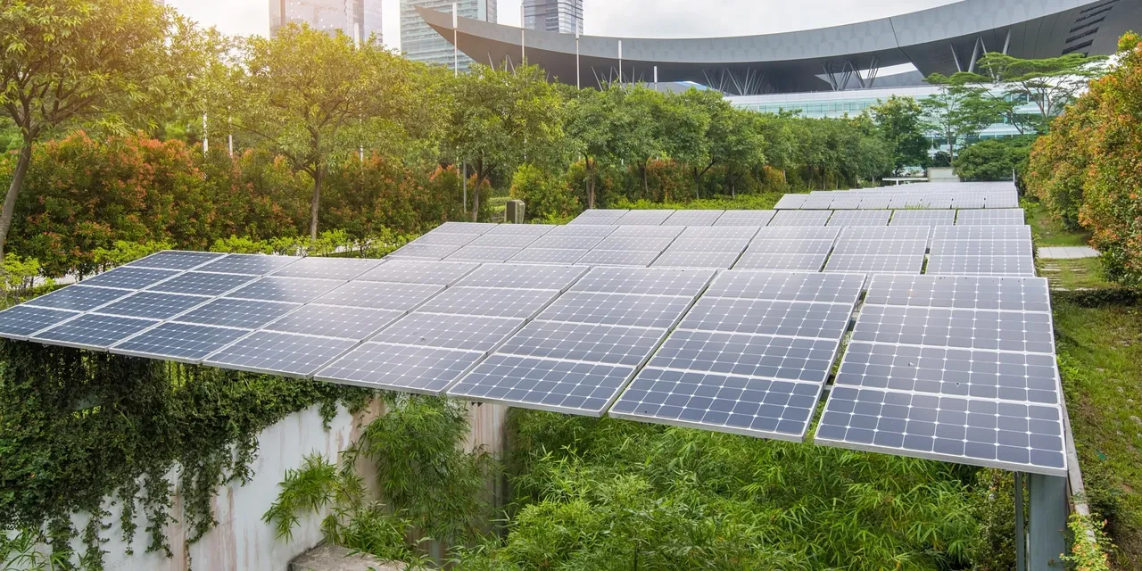 Es werden Solarpanels und im Hintergrund Hochhäuser einer Großstadt dargestellt.