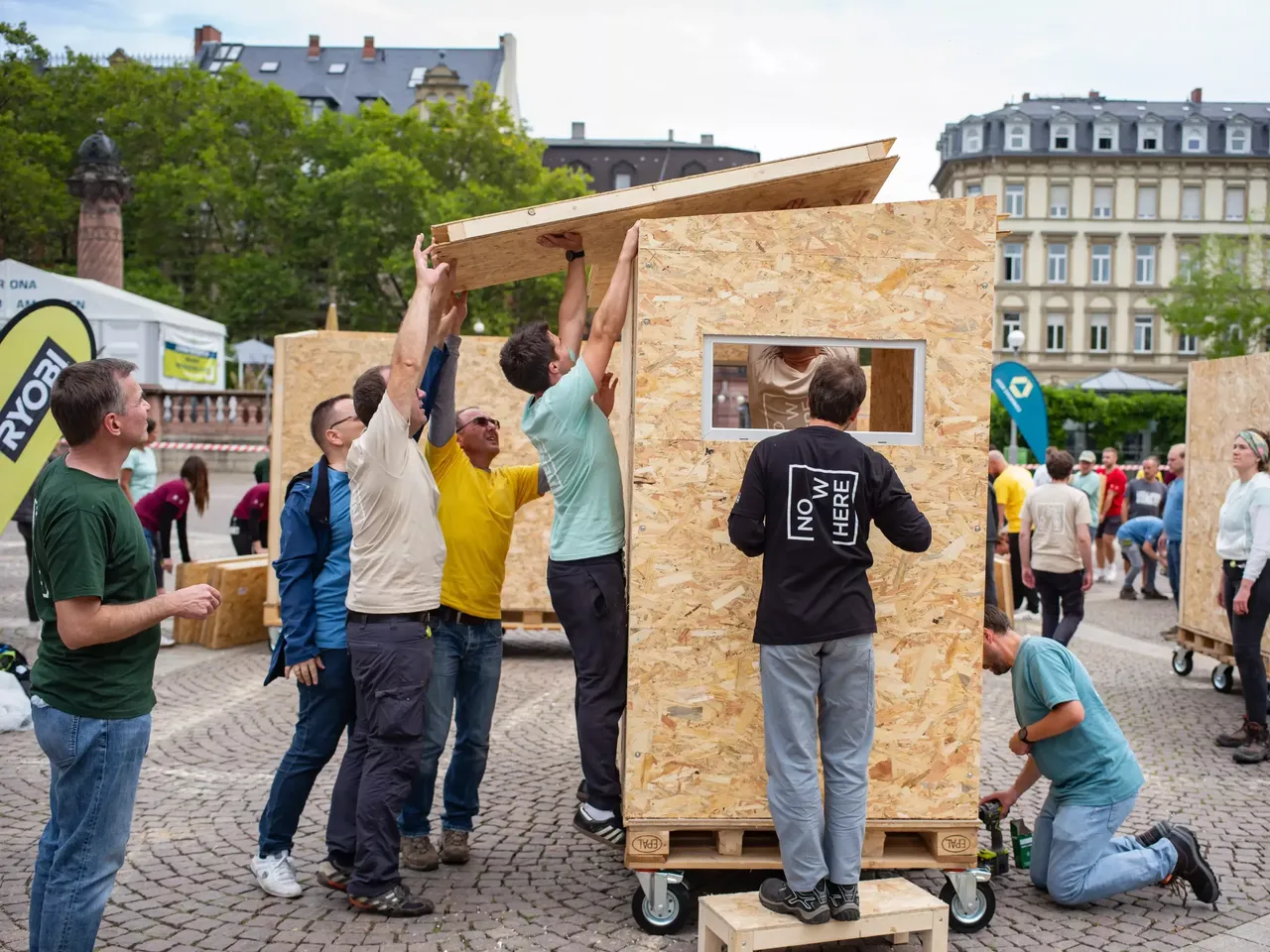 Commerz Real Mitarbeiter bauen in Teamarbeit Little Home Obdachlosen-Unterkünfte