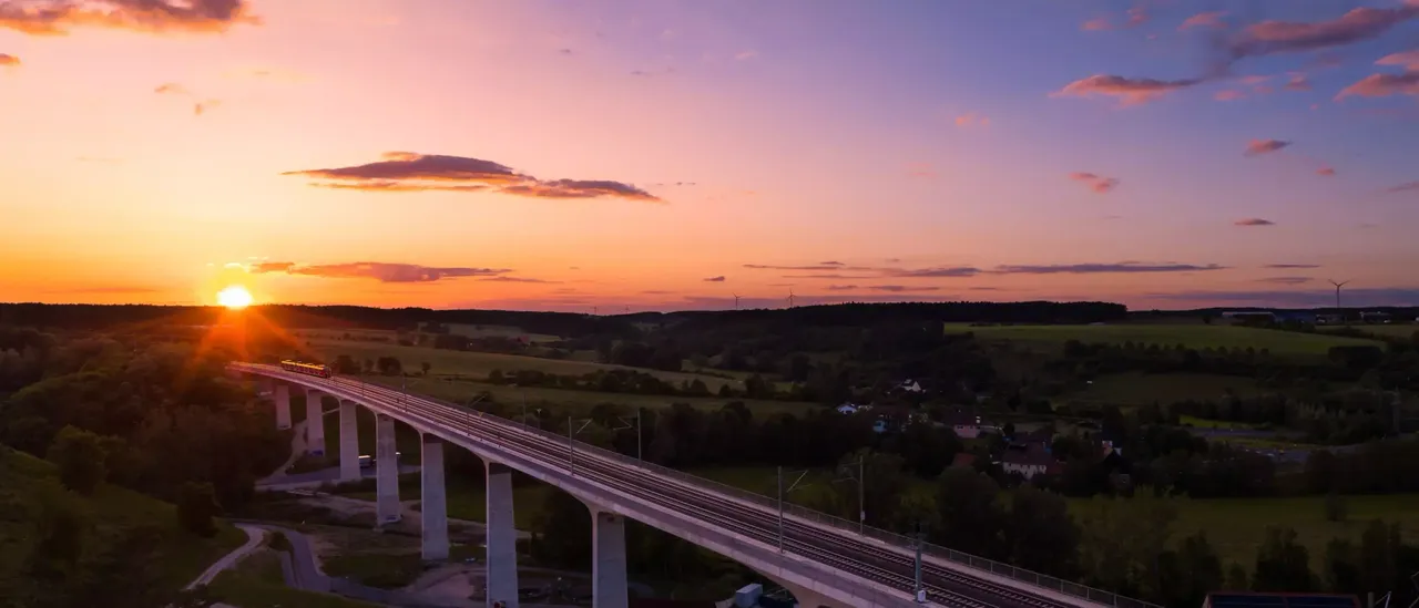 klimaVest: eine Brücke aus der Vogelperspektive im Sonnenuntergang.