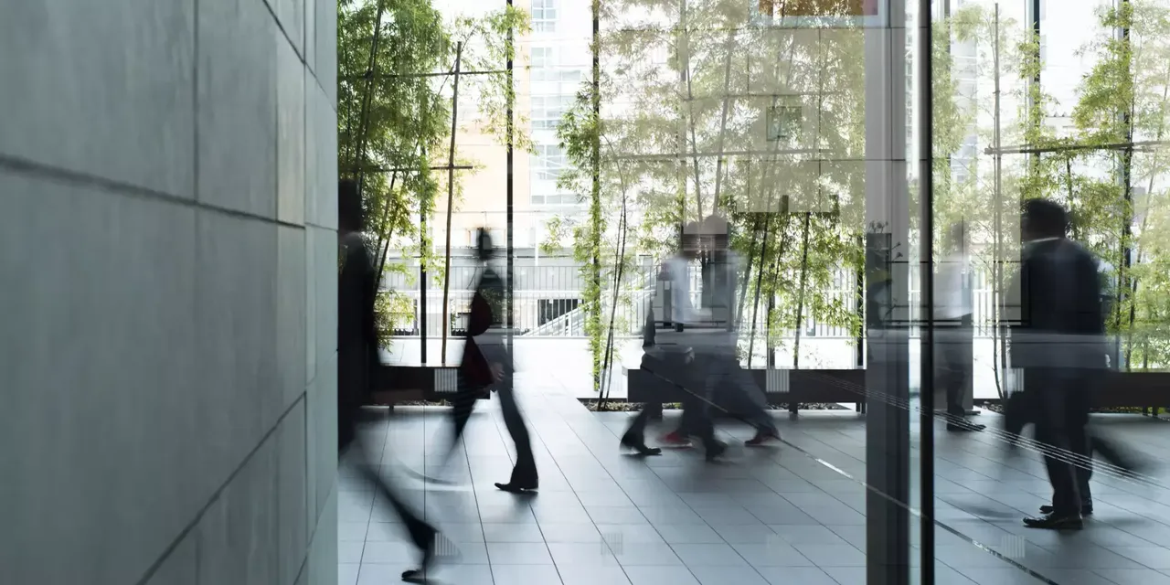 klimaVest: Menschen laufen durch ein Bürogebäude.