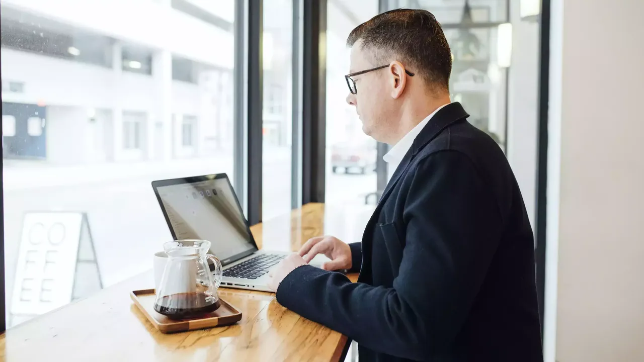 Am Laptop arbeitender Mann mittleren Alters im Cafe