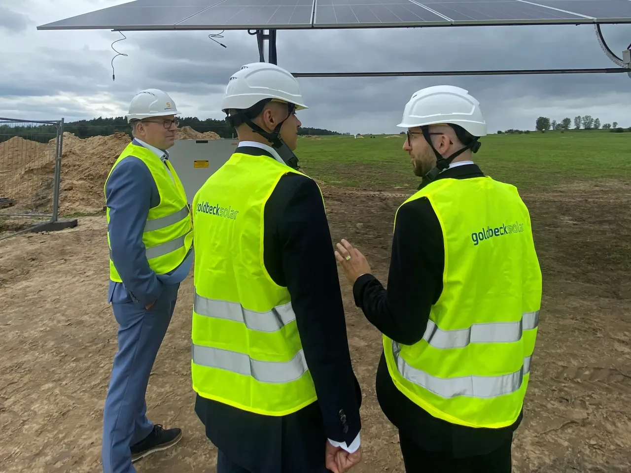 Es werden Projektbeteiligte im Gespräch vor den Solarmodulen des Agri-PV-Projekts in Berlin-Schönefeld dargestellt.