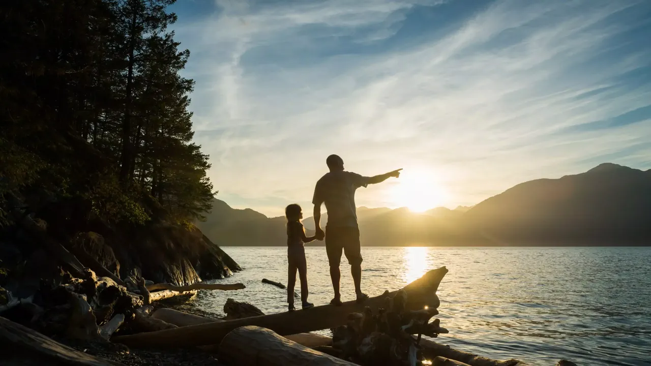 Ein Vater mit seinem Sohn an einem Ufer, die auf das Meer blicken