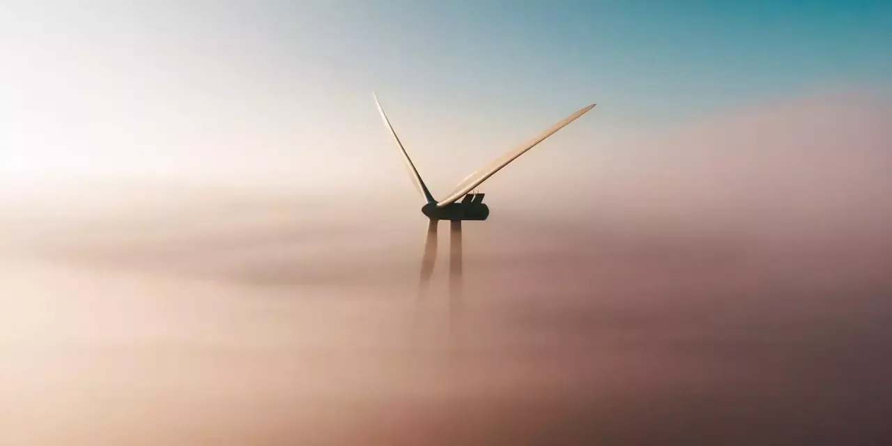 Ein Windrad ragt aus einer Wolke in den Himmel