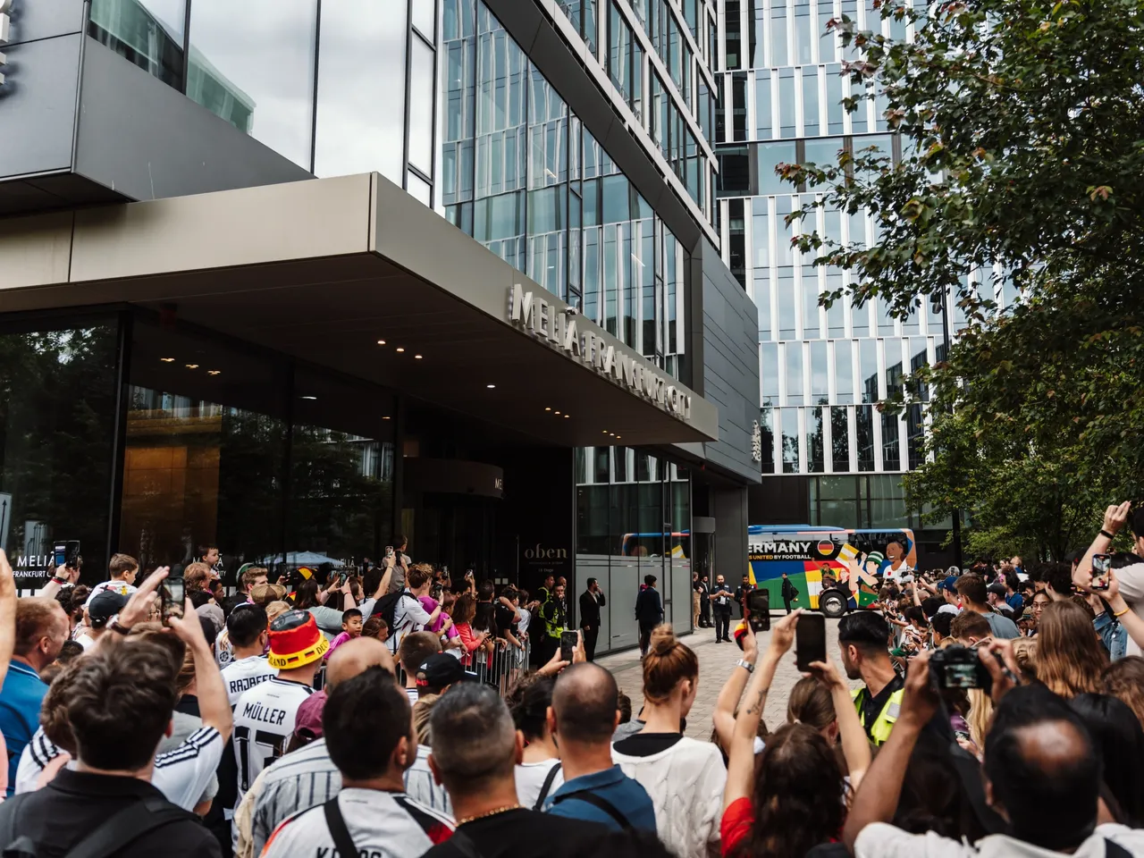 Im Vordergrund stehen Fans der deutschen Nationalmannschaft vor dem Haupteingang der hausInvest-Immobilie One Forty West in Frankfurt.