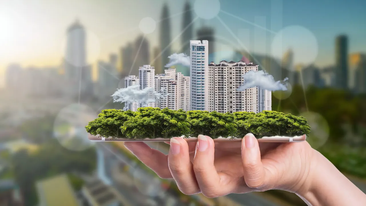 Es werden Immobilienmodelle mit Bezug zum Thema Nachhaltigkeit auf einer Handfläche abgebildet