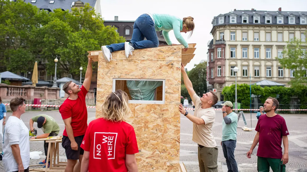 Commerz Real Mitarbeiter bauen in Teamarbeit Little Home Obdachlosen-Unterkünfte