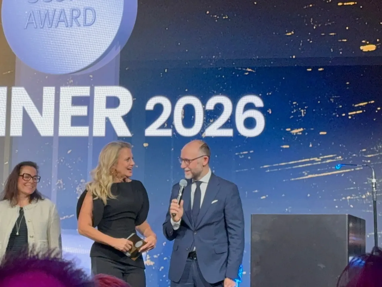 Es werden im Rahmen der Scope Award-Verleihung 2026 auf der Bühne mehrere Personen dargestellt, unter anderem Moderatorin Barbara Schöneberger im Interview mit hausInvest Fondsmanager Mario Schüttauf.