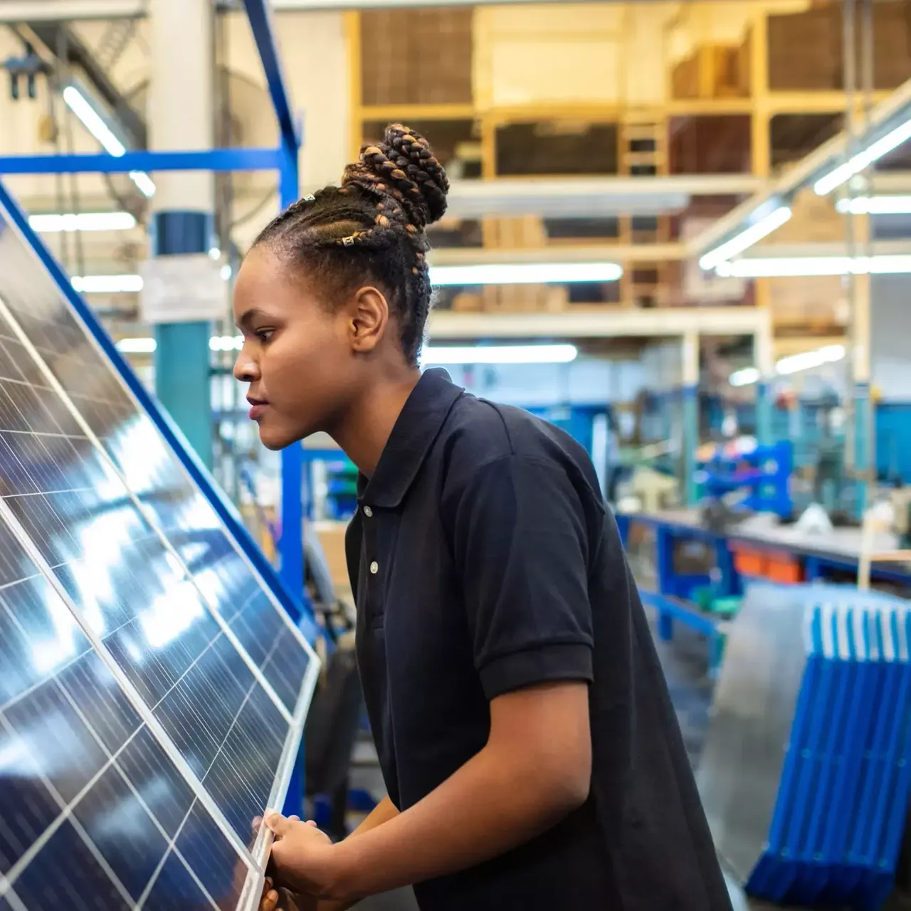 Junge Frau arbeitet an einem Solarpanel in einer Fabrik