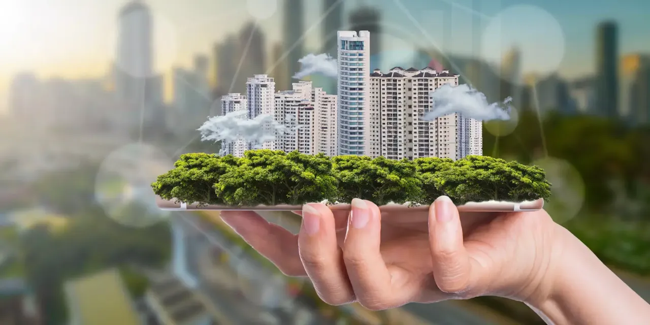 Es werden Immobilienmodelle mit Bezug zum Thema Nachhaltigkeit auf einer Handfläche abgebildet
