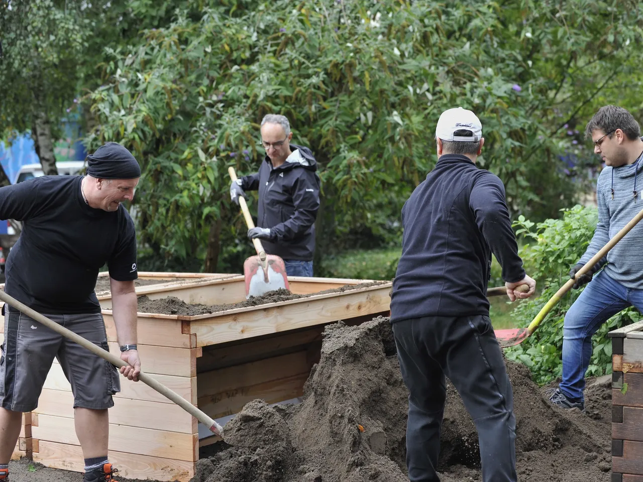 Es werden Mitarbeiterinnen und Mitarbeiter bei Gartenarbeiten im Rahmen des Commerz Real Social Days 2024 in Düsseldorf dargestellt.