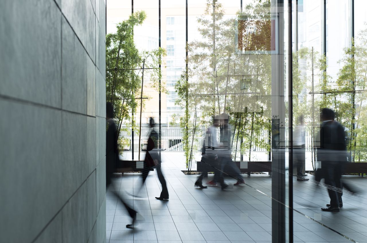 Detail eines Büro Gebäudes mit Pflanzen und Menschen in Bewegung