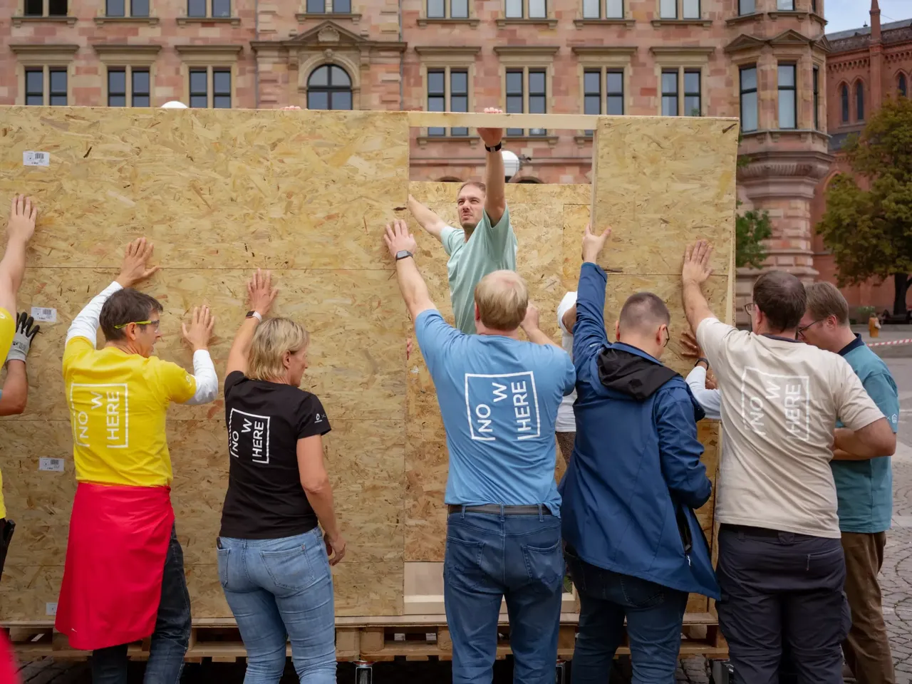 Commerz Real Mitarbeiter bauen in Teamarbeit Little Home Obdachlosen-Unterkünfte